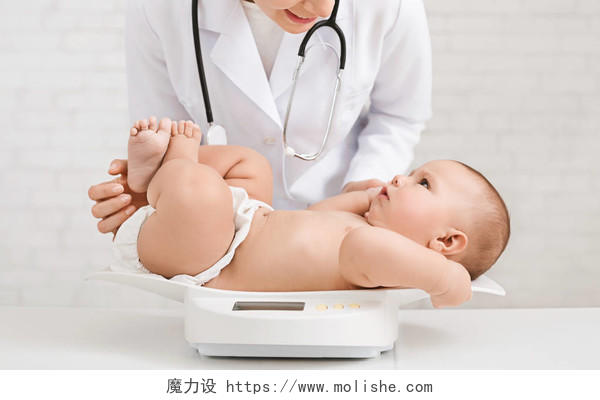 在诊所体检可爱的小宝宝躺在秤上儿科医生
